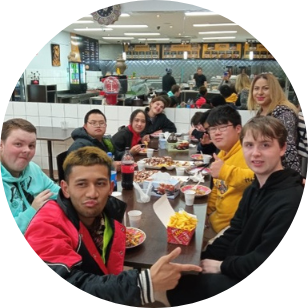 Group of young people looking at the camera and smiling while enjoy a meal together