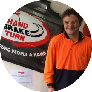 Brayden standing in front of the Hand Break Turn sign, looking at the camera and smiling. 