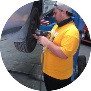 Next Step Participant wearing a yellow shirt working on the tyre of a car with an impact gun.